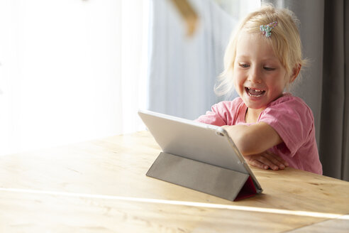 Porträt eines blonden kleinen Mädchens, das zu Hause ein digitales Tablet benutzt - GAF00099