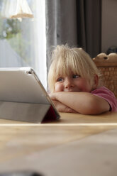 Porträt eines blonden kleinen Mädchens, das zu Hause ein digitales Tablet benutzt - GAF00101