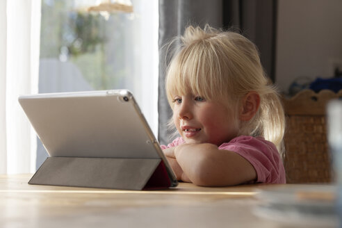 Porträt eines blonden kleinen Mädchens, das zu Hause ein digitales Tablet benutzt - GAF00104