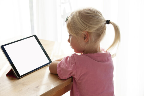 Profile of blond little girl using digital tablet at home stock photo