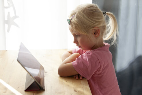 Profil eines blonden kleinen Mädchens, das zu Hause ein digitales Tablet benutzt - GAF00106