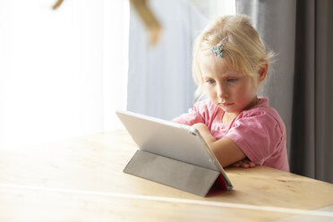 Porträt eines blonden kleinen Mädchens, das zu Hause ein digitales Tablet benutzt - GAF00107