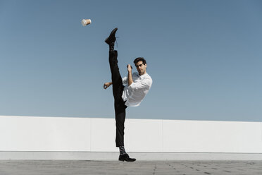 Artist practising on roof terrace with disposable cup - AFVF02658