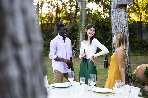 Freunde trinken Bier bei einem Sommeressen im Garten, lizenzfreies Stockfoto