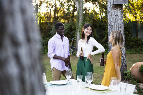 Freinds drinking beer at a summer dinner in the garden - ABZF02257