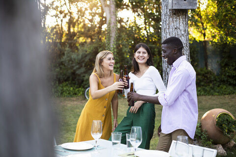 Freunde stoßen mit Bier bei einem Sommeressen im Garten an, lizenzfreies Stockfoto