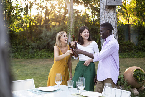 Freinds toasting with beer at a summer dinner in the garden - ABZF02261