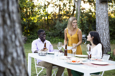 Gastgeber servieren Essen bei einem Sommerdinner im Garten - ABZF02264