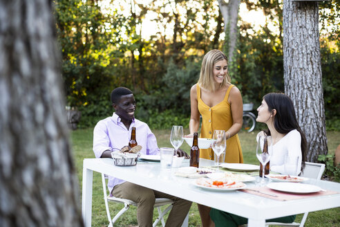 Host serving food at a summer dinner in the garden - ABZF02264