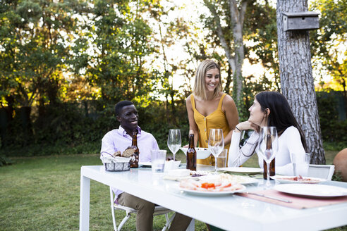 Host serving food at a summer dinner in the garden - ABZF02266