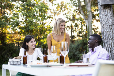 Gastgeber servieren Essen bei einem Sommerdinner im Garten - ABZF02268