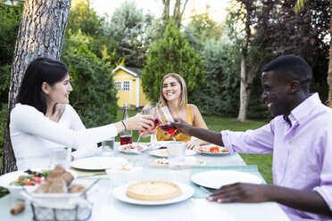 Freunde stoßen mit Wein bei einem Sommeressen im Garten an - ABZF02280