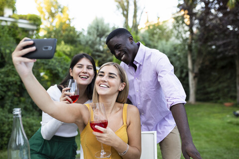 Friends having fun at a summer dinner in the garden, taking selfies stock photo