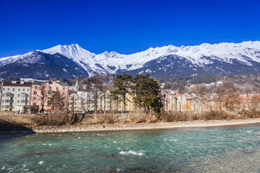 Austria, Tyrol, Innsbruck, colored buildings along the Inn river with snow-capped Alps in background - FLMF00173