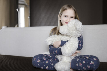 Porträt eines lächelnden kleinen Mädchens, das einen Pyjama mit Blumenmuster trägt und einen weißen Teddybären hält - EYAF00077