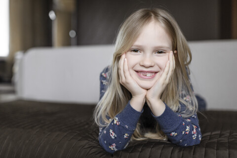 Porträt eines lächelnden kleinen Mädchens mit Zahnlücke und Kopf in den Händen, lizenzfreies Stockfoto