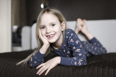 Portrait of smiling little girl with tooth gap relaxing on couch at home - EYAF00082