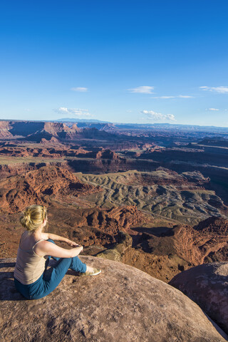 USA, Utah, Frau an einem Aussichtspunkt mit Blick auf die Canyonlands und den Colorado River im Dead Horse State Park, lizenzfreies Stockfoto