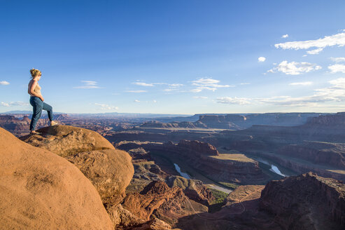 USA, Utah, Woman at a overlook over the canyonlands and the Colorado river from the Dead Horse State Park - RUNF01693