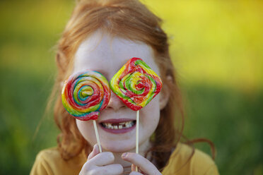 Happy girl covering her eyes with lollipops - GAF00110