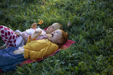 Two sisters lying in a field holding lollipops - GAF00115