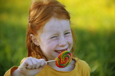 Portrait of happy girl eating a lollipop - GAF00116