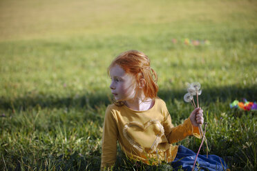 Rothaariges Mädchen sitzt mit Pusteblume im Feld - GAF00123