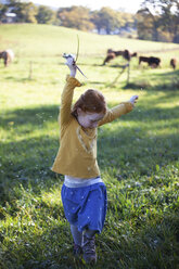 Redheaded girl dancing in field with blowball - GAF00125