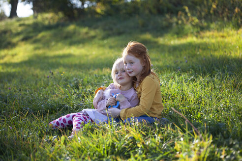 Two sisters cuddling in field - GAF00127