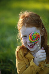 Happy girl covering her eye with lollipop - GAF00129