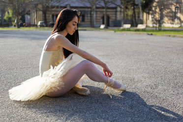 Italy, Verona, young woman sitting down in the city wearing ballet dress - GIOF05956