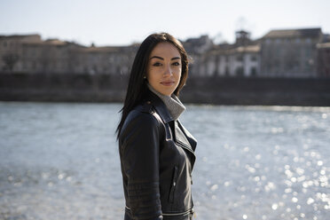 Italy, Verona, portrait of smiling young woman at the riverside - GIOF05961