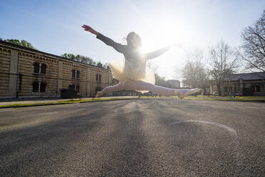 Italy, Verona, Ballerina dancing in the city jumping midair - GIOF05983