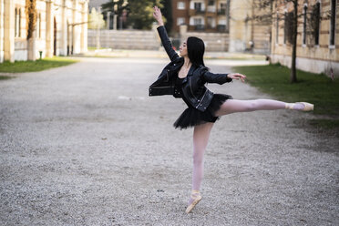 Italy, Verona, Ballerina dancing in the city wearing leather jacket and tutu - GIOF05992