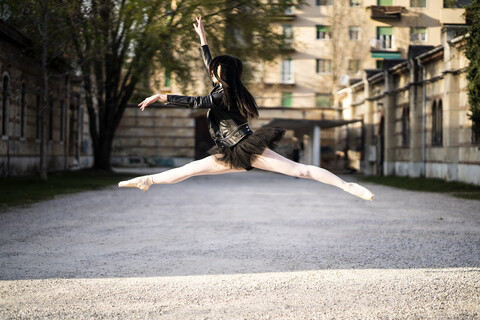 Italien, Verona, Ballerina in Lederjacke und Tutu springt in der Luft, lizenzfreies Stockfoto