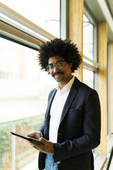 Porträt eines selbstbewussten Geschäftsmannes, der am Fenster steht und ein Tablet benutzt - VABF02277