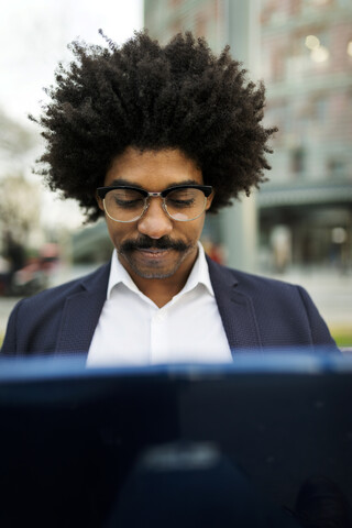 Spain, Barcelona, portrait of businessman in the city using laptop stock photo