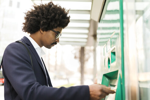 Spanien, Barcelona, Geschäftsmann benutzt Fahrkartenautomat an Straßenbahnhaltestelle in der Stadt - VABF02295