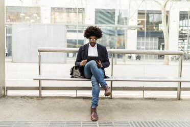 Spanien, Barcelona, Geschäftsmann in der Stadt sitzt auf einer Bank am Bahnhof und benutzt ein Tablet - VABF02298