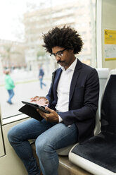 Spanien, Barcelona, Geschäftsmann in einer Straßenbahn mit Tablet - VABF02299