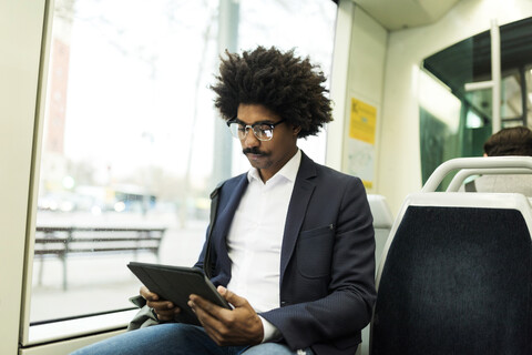 Spanien, Barcelona, Geschäftsmann in einer Straßenbahn mit Tablet, lizenzfreies Stockfoto