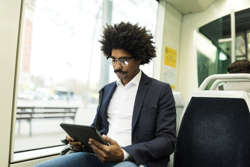 Spanien, Barcelona, Geschäftsmann in einer Straßenbahn mit Tablet - VABF02300