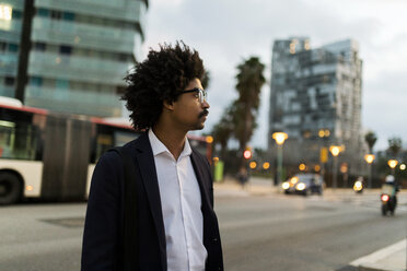 Spain, Barcelona, businessman standing at a street in the city at dusk - VABF02315