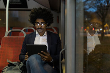 Spanien, Barcelona, Geschäftsmann in einer Straßenbahn bei Nacht mit Tablet - VABF02320