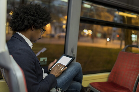 Spanien, Barcelona, Geschäftsmann in einer Straßenbahn bei Nacht mit Tablet, lizenzfreies Stockfoto