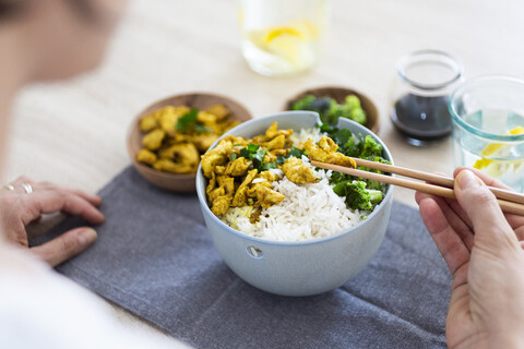 Curryhuhn, Brokkoli und Reis, Frau mit Stäbchen, lizenzfreies Stockfoto
