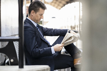 Geschäftsmann liest Zeitung auf dem Bahnsteig - DIGF06423