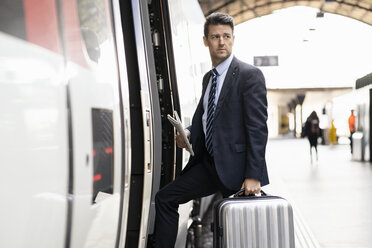 Geschäftsmann mit Koffer beim Einsteigen in den Zug - DIGF06425