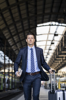 Businessman walking with suitcase on station platform - DIGF06426
