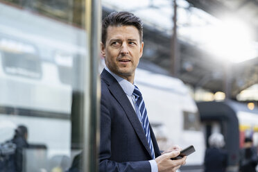 Businessman with cell phone at train station - DIGF06430